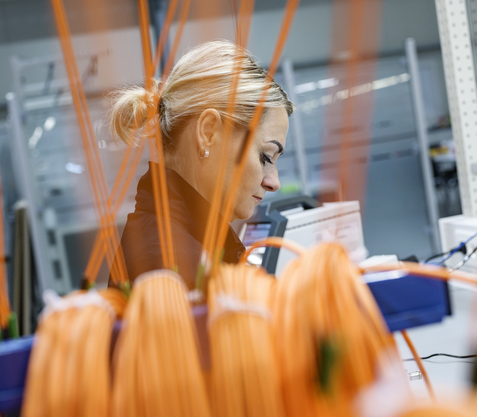 An employee preparing fiber optic cables for assembly.